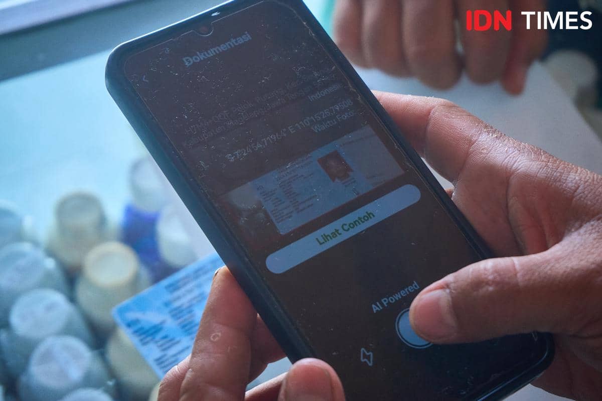 Petugas kios Penerima Pupuk pada Titik Serah (PPTS) UD Jambul, Fakhur Arif (kanan) memindai KTP petani satu per satu menggunakan aplikasi i-Pubres saat penebusan pupuk bersubsidi di Desa Pucang, Secang, Magelang, Senin (22/12/2025). (IDN Times/Dhana Kencana)