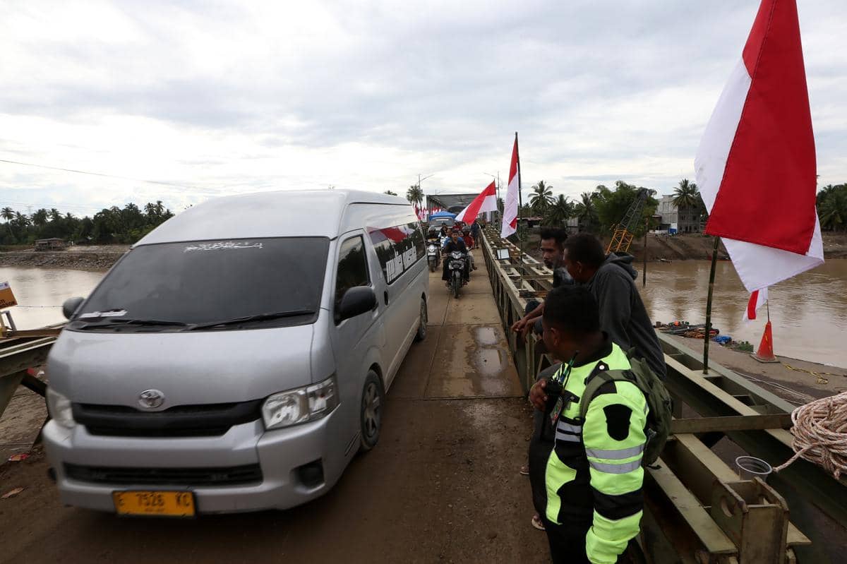 Warga dan kendaraan melewati jembatan darurat bailey Krueng Tingkeum yang baru selesai dibangun di Kuta Blang, Bireuen, Aceh, Sabtu (27/12/2025). Pemerintah bersama TNI/Polri telah menyelesaikan jembatan bailey Krueng Tingkeum, Kuta Blang (ANTARA FOTO/Irwansyah Putra)