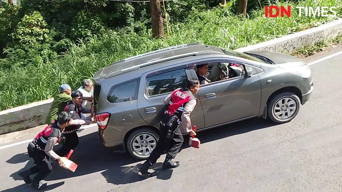 Tim Drogba Sat Samapta Polres Magetan dorong mobil wisatawan yang tidak kuat menanjak di jalur wisata Sarangan. IDN Times/Riyanto.