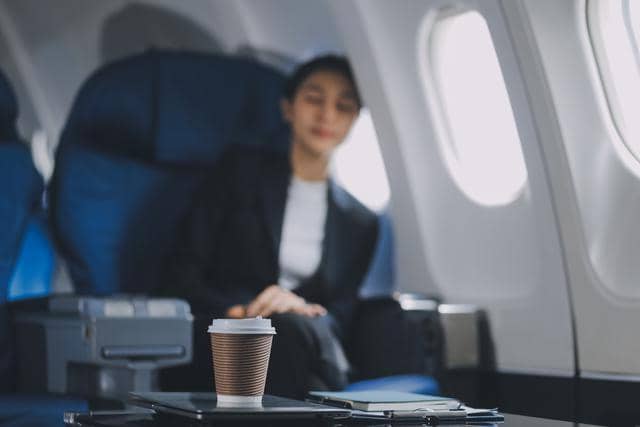 Seorang perempuan tidur bersender di jendela pesawat.