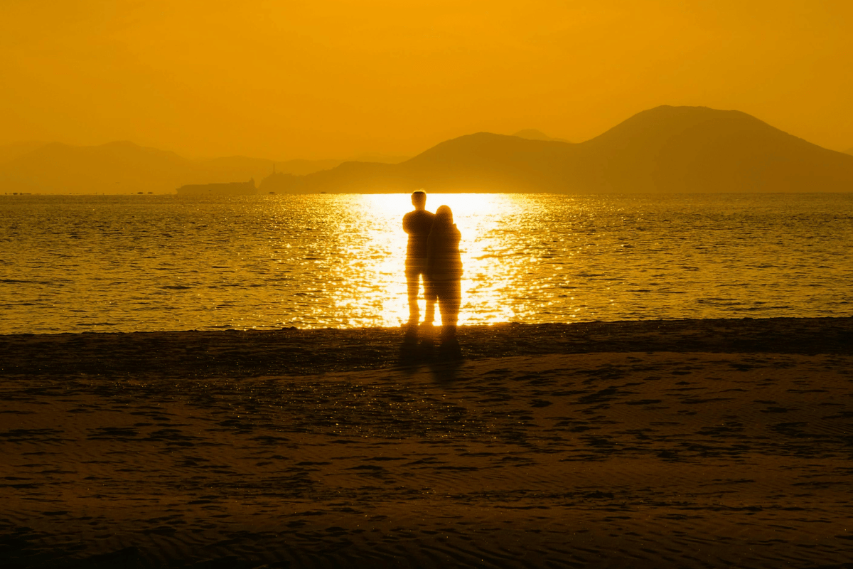 Foto pasangan bersama di pantai saat matahari terbenam