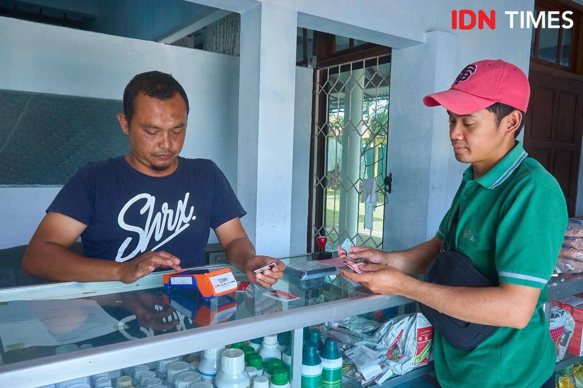 Petani muda yang juga Bendahara Kelompok Tani Maju Mulyo, Muhammad Amanullah (kanan) menebus pupuk bersubsidi di kios Penerima Pupuk pada Titik Serah (PPTS) UD Jambul di Desa Pucang, Secang, Kabupaten Magelang, Senin (22/12/2025). (IDN Times/Dhana Kencana)