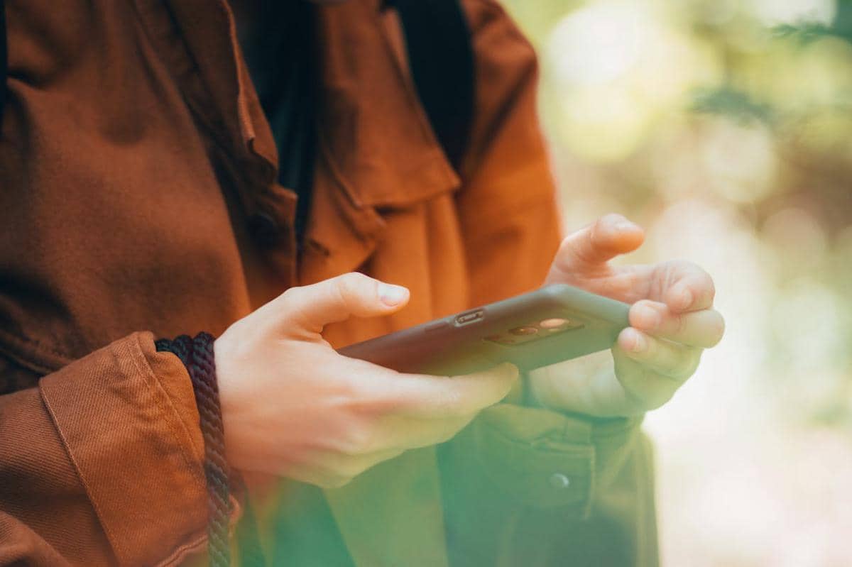 Ilustrasi Seseorang Menggunakan Smartphone sebagai Alat Kerja Digital dengan Latar Aktivitas Produktif.