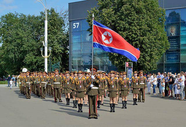 Grup Musik Militer Pusat Tentara Rakyat Korea sebelum pertunjukan. Pembawa panji dengan bendera Korea Utara berada di latar depan. (Dmitry Ivanov., CC BY-SA 4.0, via Wikimedia Commons)