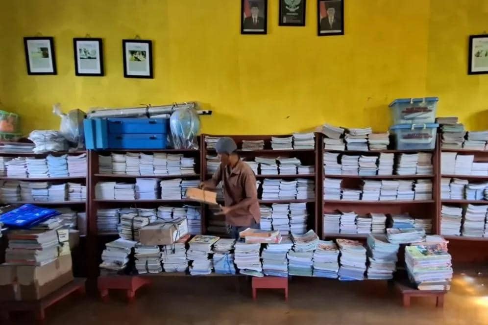 Penjaga sekolah merapihkan buku-buku yang terdampak banjir di ruang perpustakaan SDN Pamarican 2, Kota Serang, Banten, Senin (5/1/2025) 