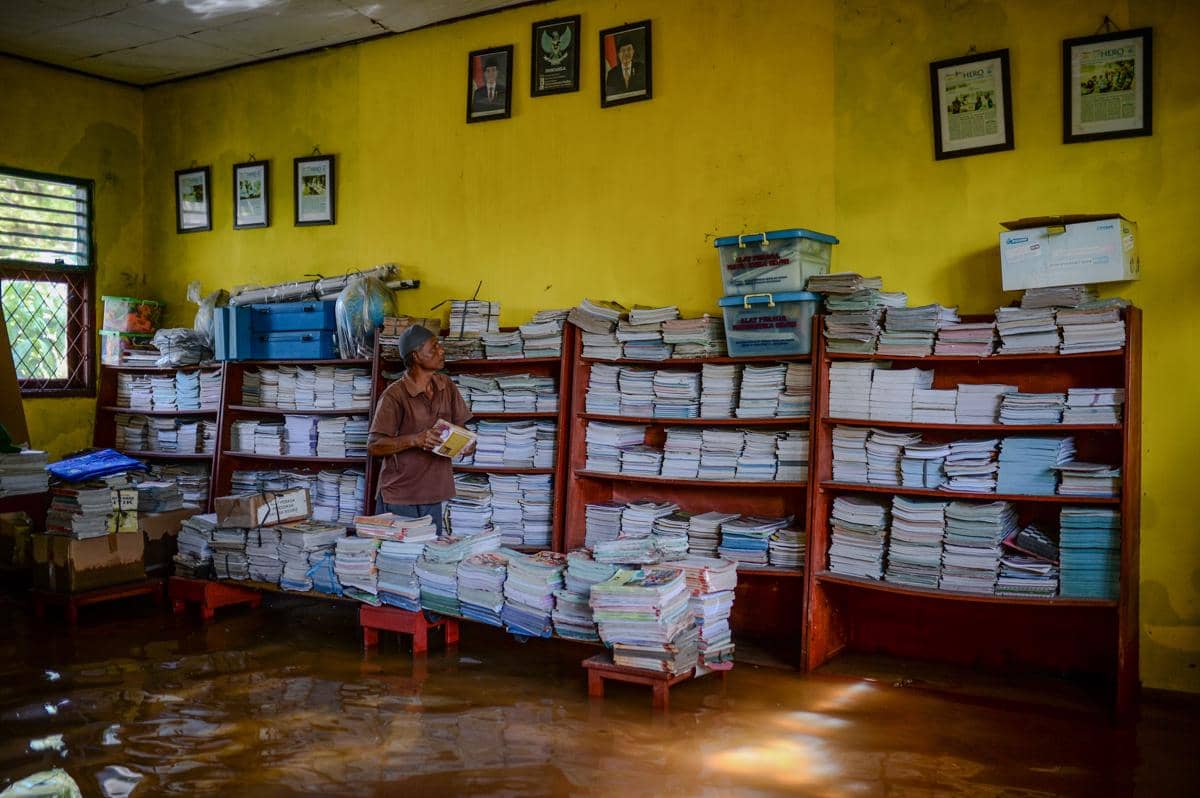 Penjaga sekolah merapikan meja saat banjir masih merendam ruang kelas di SD Negeri Pamarican 2, Kota Serang, Banten, Senin (5/1/2026). Menurut pihak sekolah, banjir yang terjadi sejak Jumat (2/1) tersebut hingga kini masih merendam enam ruang kelas dan satu ruang perpustakaan sehingga menyebabkan sebanyak 234 siswa terpaksa mengikuti kegiatan belajar secara daring di rumahnya. 