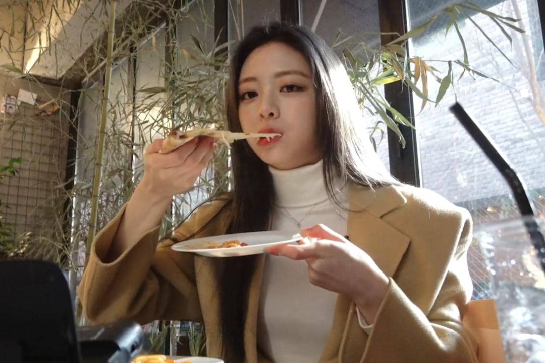 Yuna ITZY terlihat menikmati pizza dalam sebuah konten vlog individu