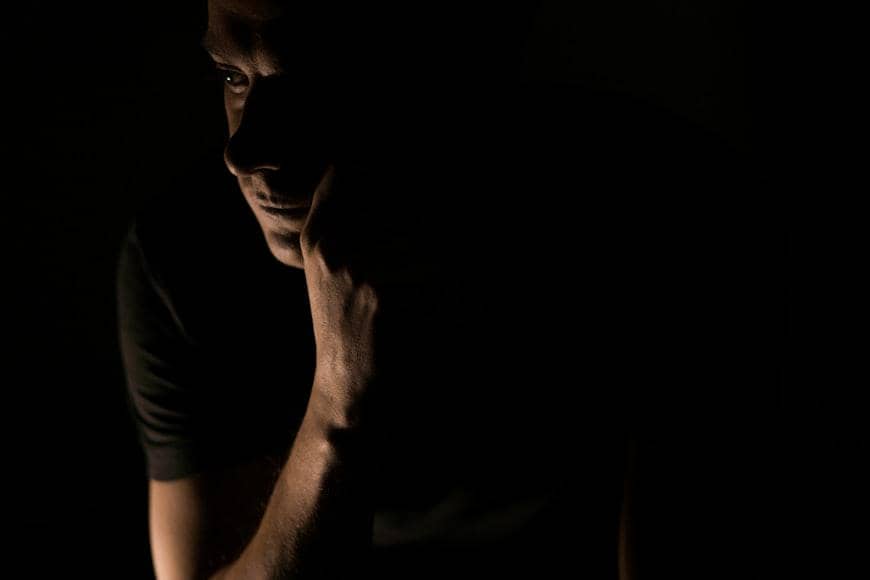 Ilutrasi pria memakai baju hitam di ruangan gelap