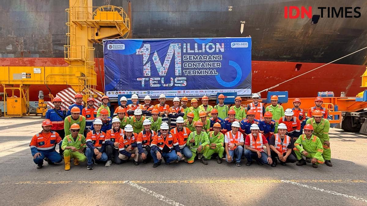 Kru Terminal Peti Kemas dan petugas keamanan foto bersama dengan latar belakang buritan kapal kargo. (IDN Times/Fariz Fardianto) 