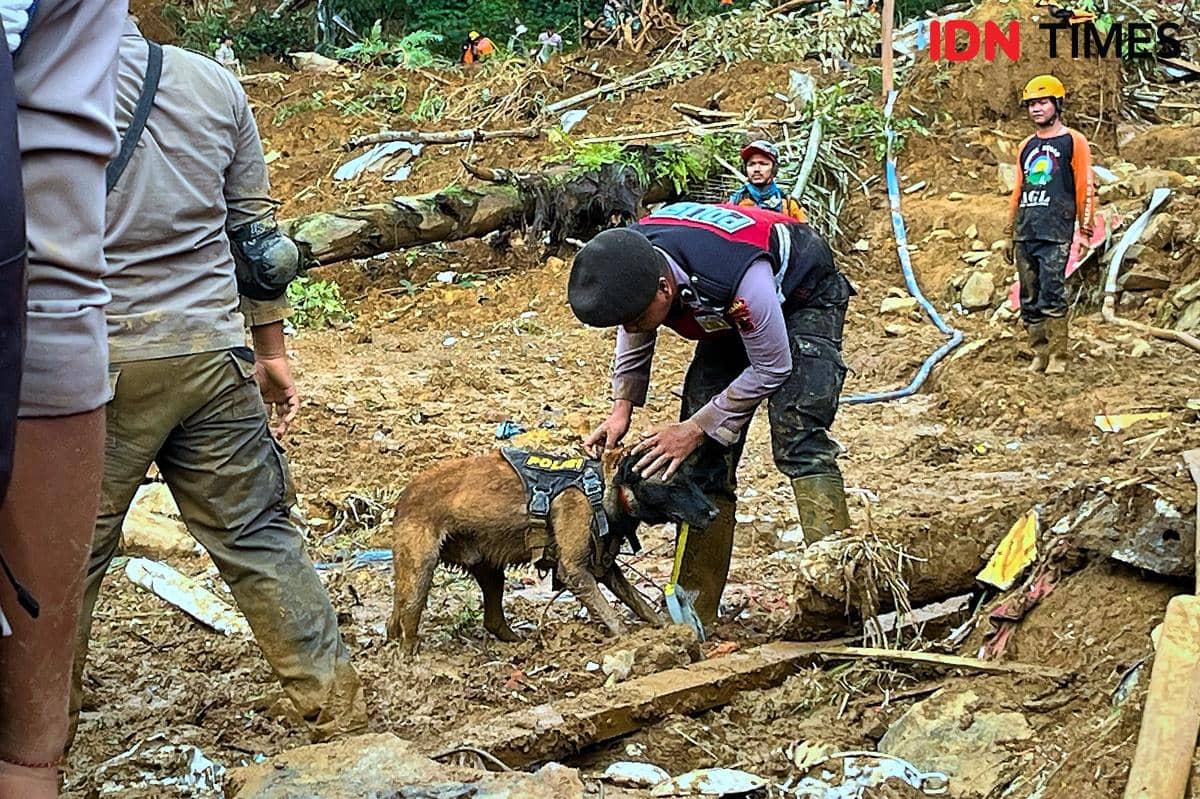 Gestur kasih sayang ditunjukkan seorang anggota Polri kepada anjing K-9 andalannya saat jeda sesaat di tengah lumpur tebal lokasi longsor ketika pencarian korban di Pekalongan, Jawa Tengah, Kamis (23/1/2025). Di balik seragam yang kotor oleh tanah, terpancar sisi humanis pengabdian Polisi yang tidak hanya menjaga ketertiban, namun juga merawat harapan hidup dan kemanusiaan bersama sahabat berkaki empatnya di medan bencana. (IDN Times/Dhana Kencana)