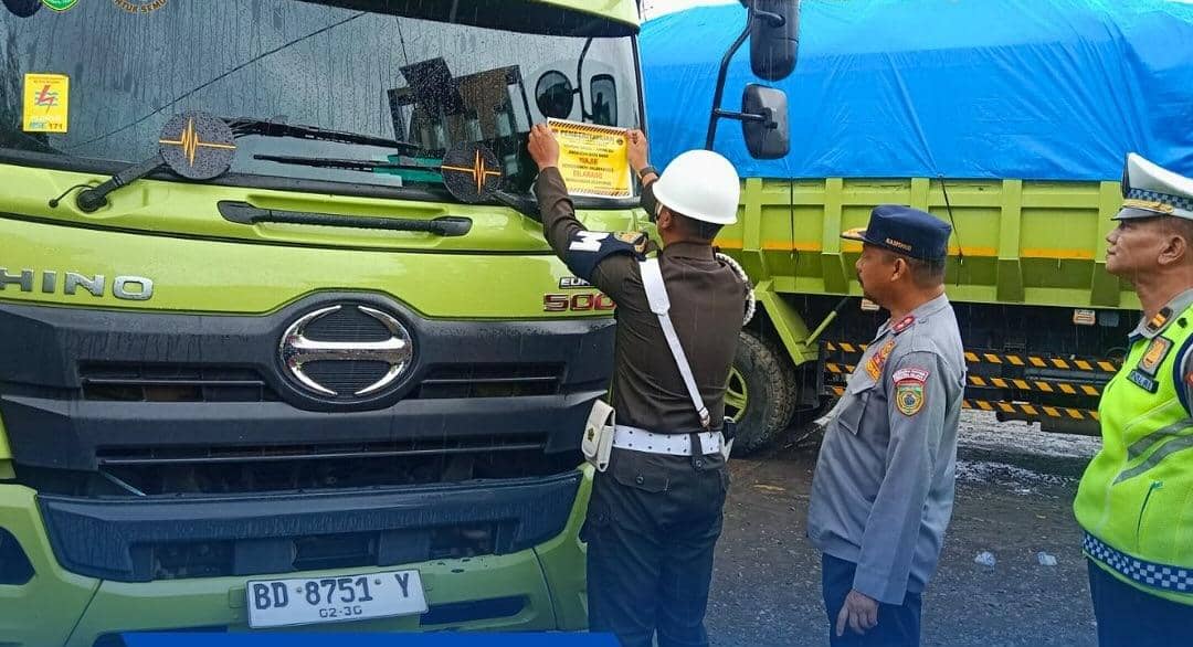 Petugas memasang stiker di truk batubara.