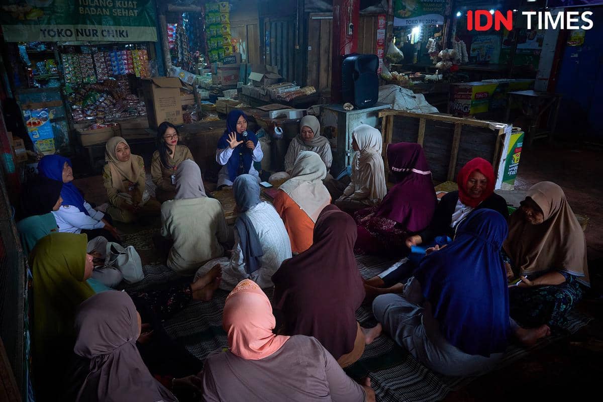 Penyuluh Agama Islam, Khoirun Nisa memandu pedagang pasar mengaji Al-Qur'an bersama dan edukasi PHBS di Pasar Mijen, Semarang, Senin (11/1/2026). (IDN Times/Dhana Kencana)