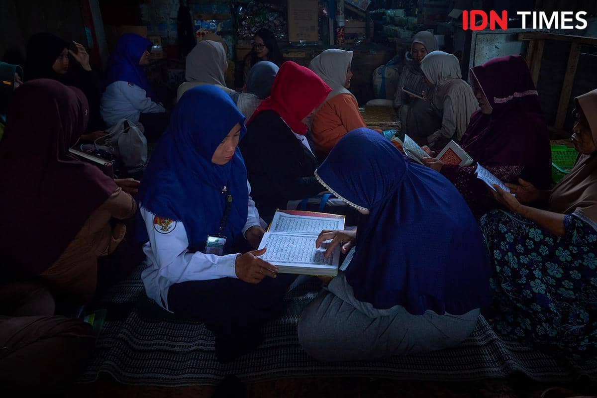 Penyuluh Agama Islam, Khoirun Nisa (kiri) memandu pedagang pasar mengaji Al-Qur'an bersama di Pasar Mijen, Semarang, Senin (11/1/2026). (IDN Times/Dhana Kencana)