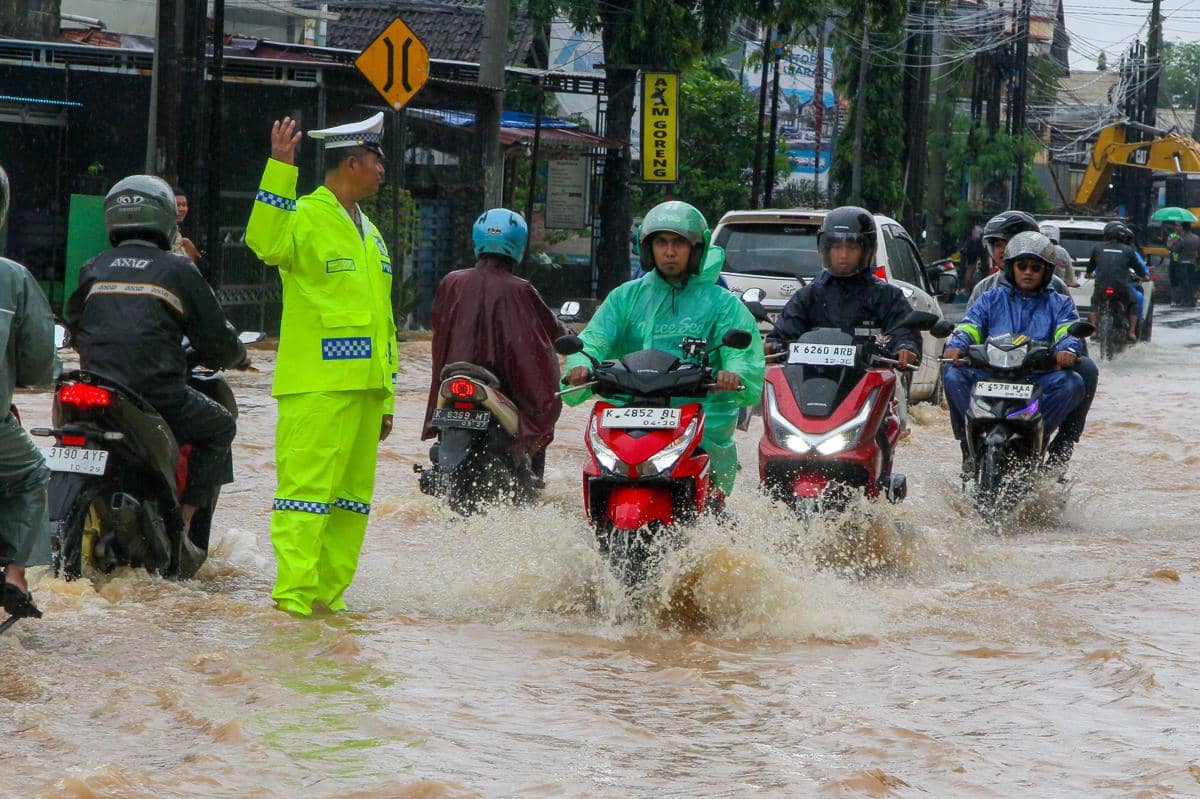 Polisi mengatur arus lalu lintas saat terjadi genangan di ruas Jalan Kudus-Pati, Desa Ngembalrejo, Kabupaten Kudus, Jawa Tengah, Senin (12/1/2026). ANTARA FOTO/Nirza