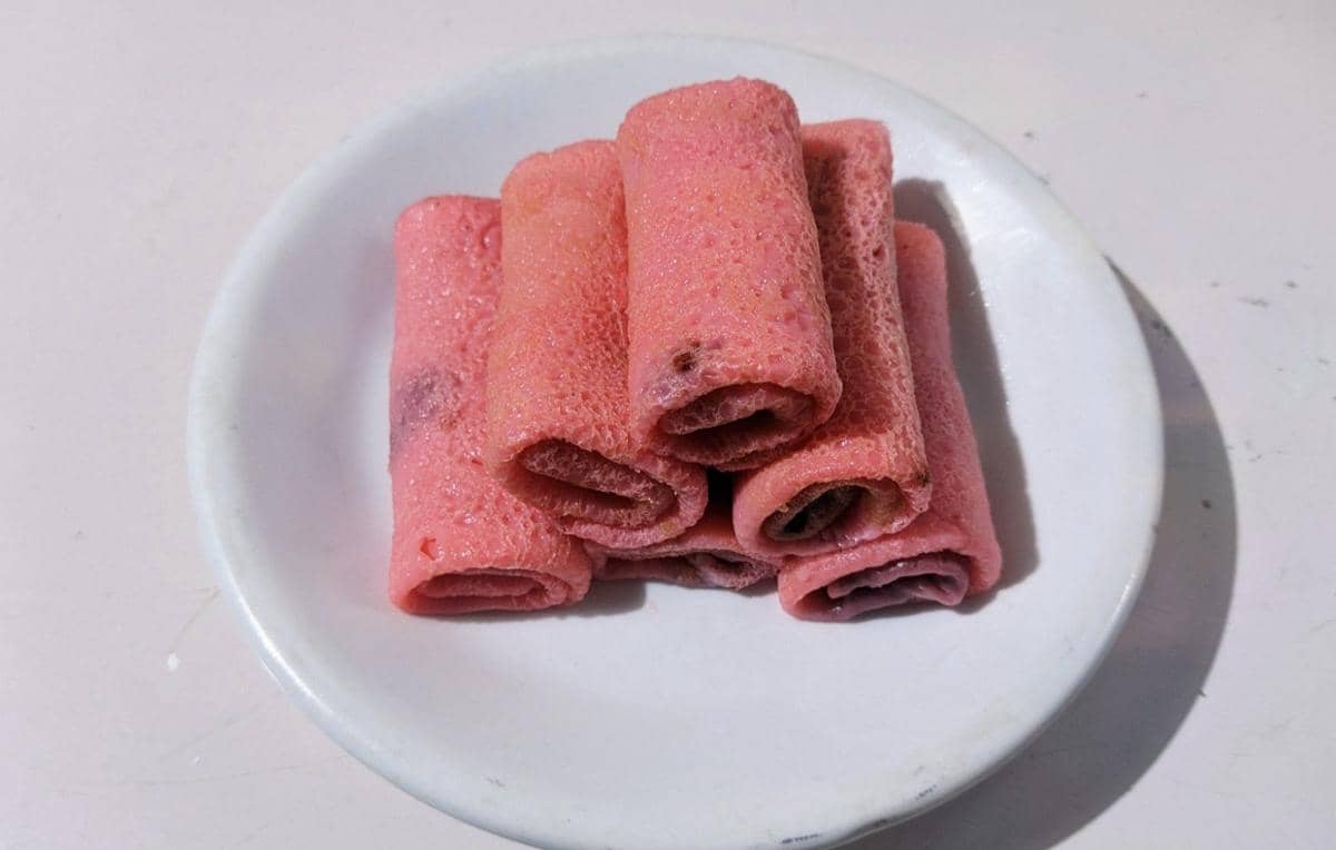 ilustrasi dadar gulung isi cokelat di atas piring putih 