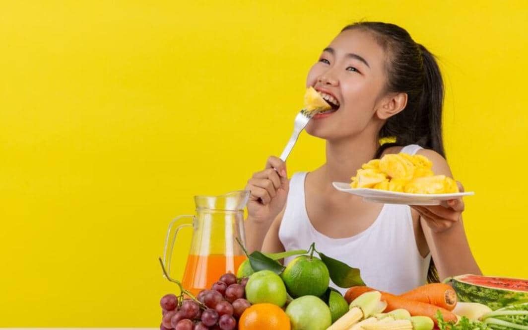 Seorang perempuan makan buah-buahan.
