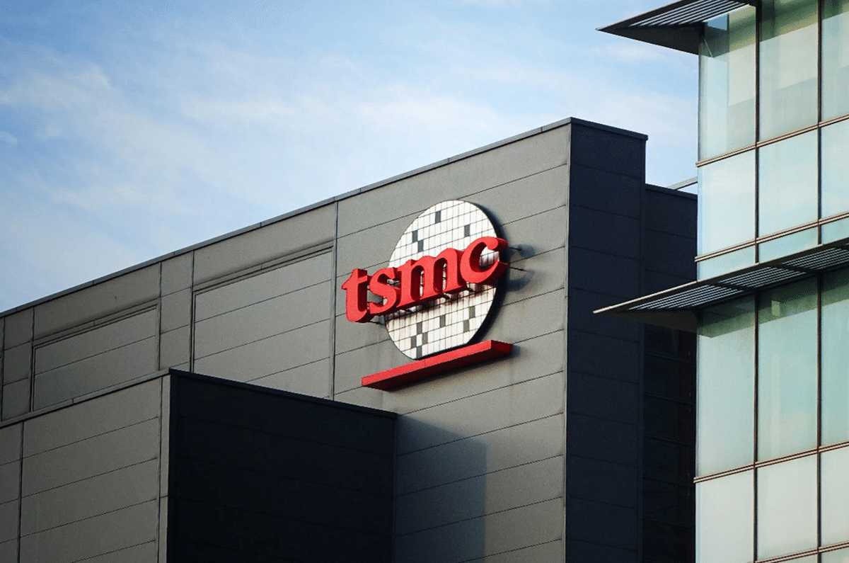 Gedung kantor TSMC dengan logo perusahaan berwarna merah di dinding luar bangunan modern berarsitektur kaca dan logam.