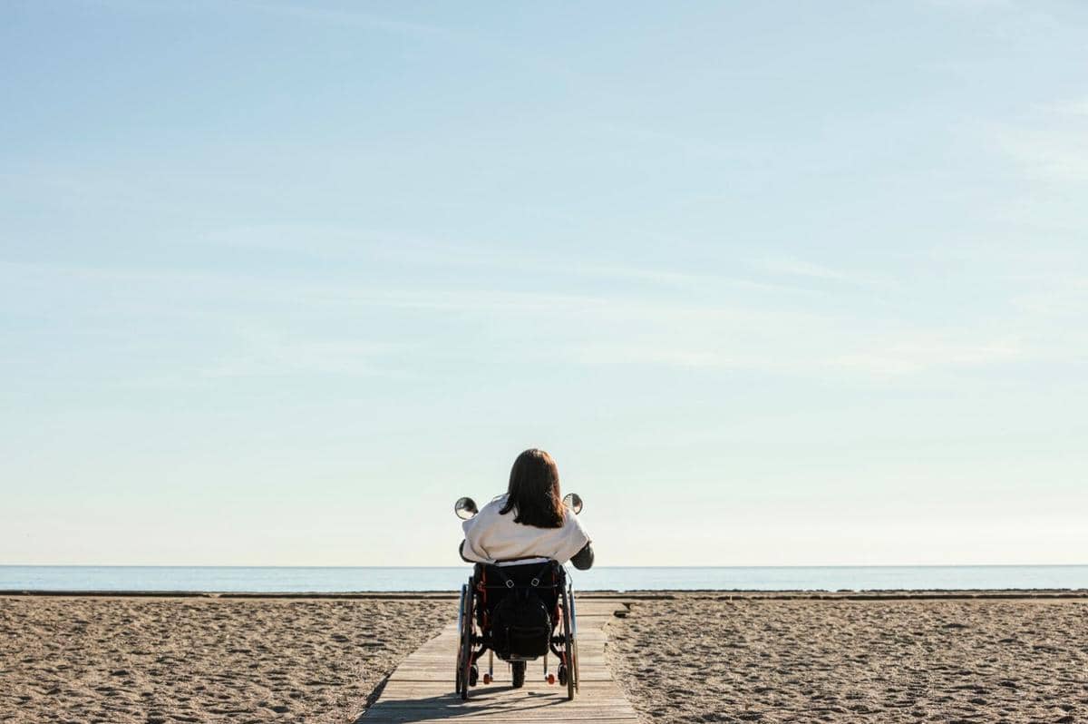 ilustrasi perempuan disabilitas di pinggir pantai