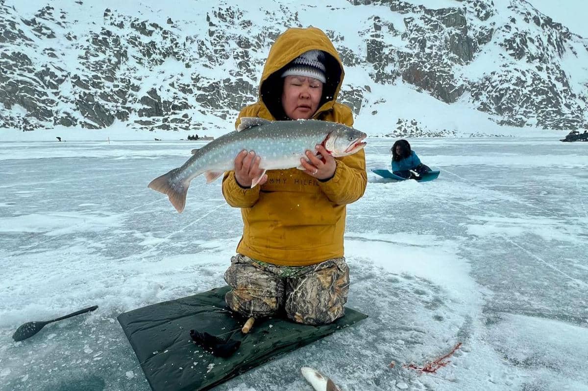 Potret orang mendapat hasil tangkapan dari ice fishing