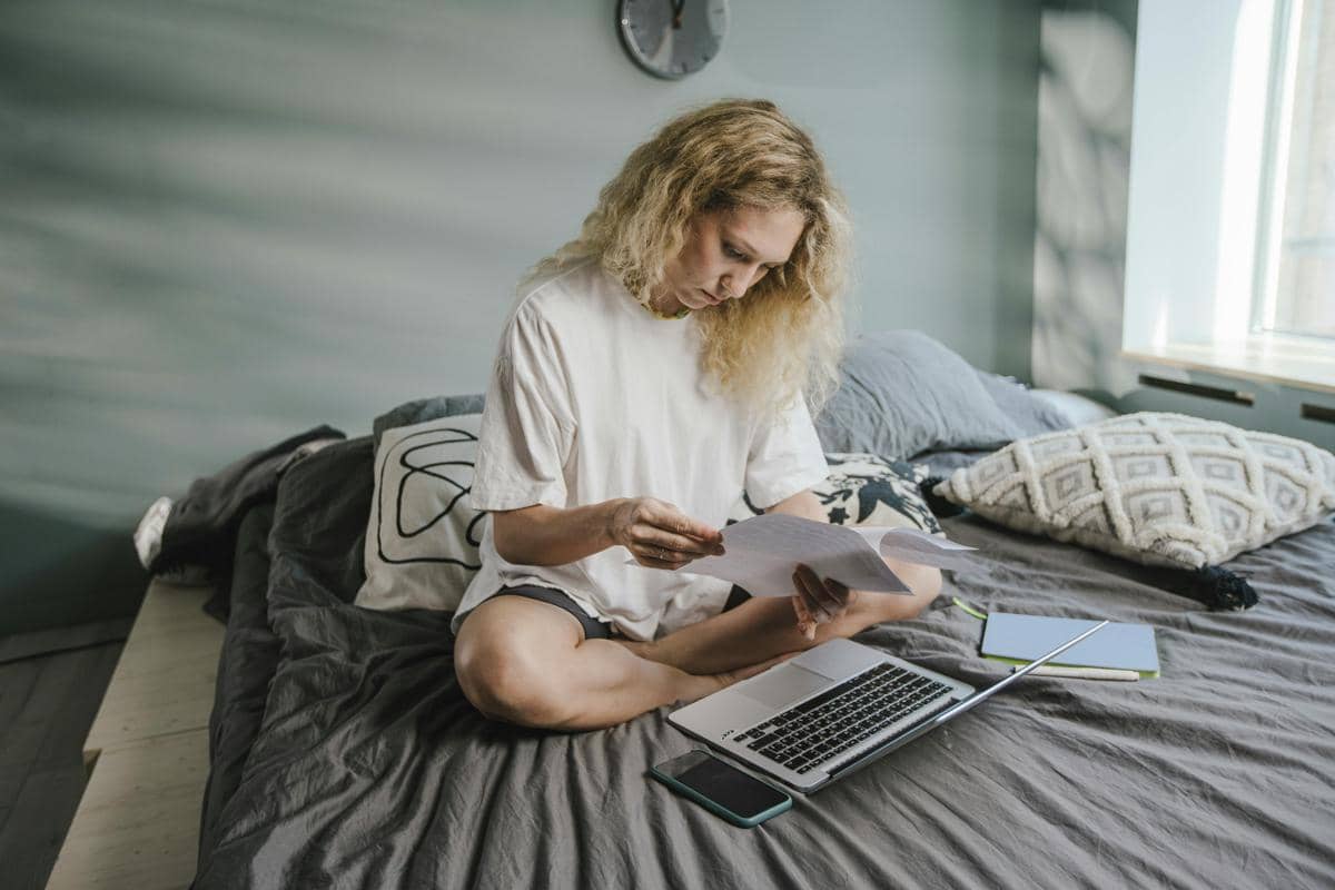 ilustrasi seorang wanita sedang mengerjakan tugas di kasur