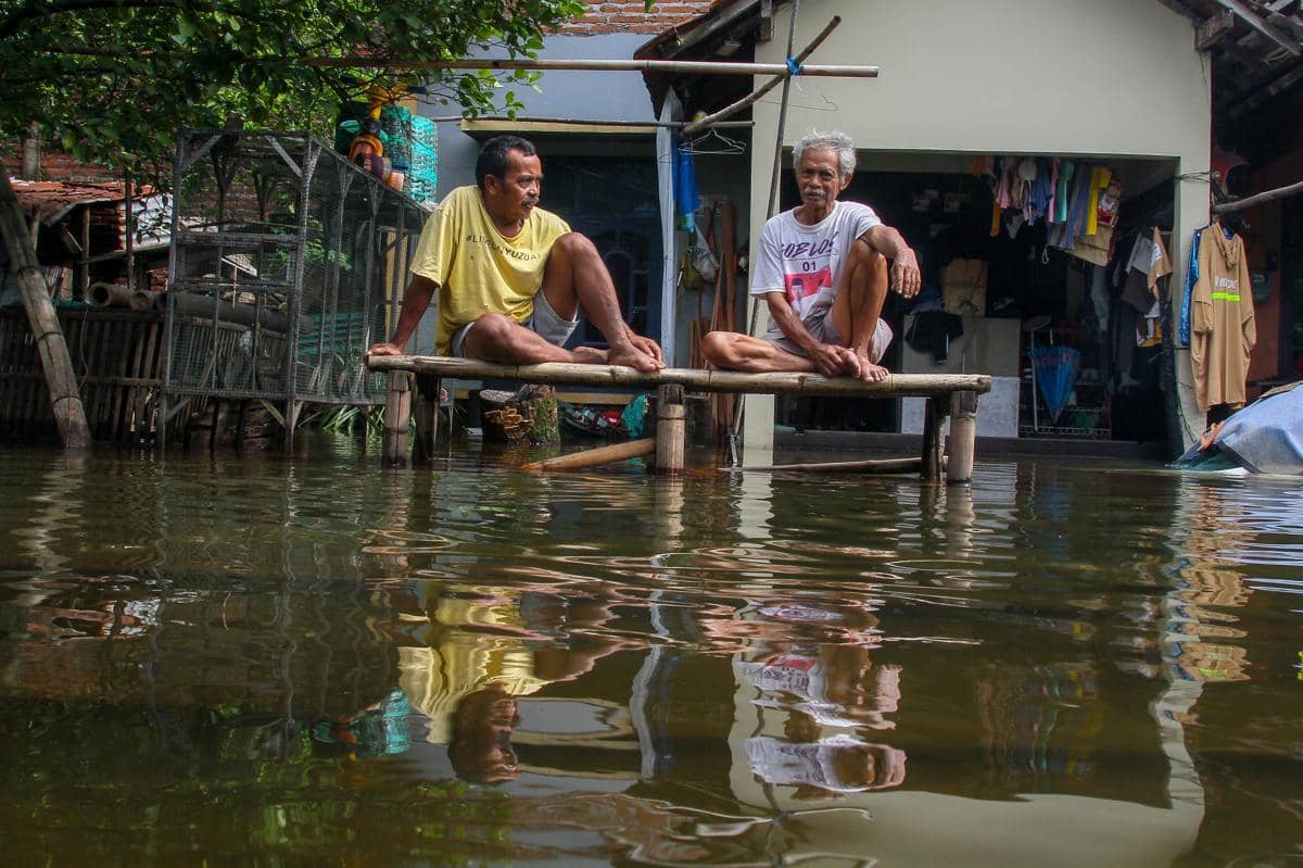 Warga berada di depan rumah yang terendam banjir di Desa Tanjungkarang, Kabupaten Kudus, Jawa Tengah, Sabtu (17/1/2026). (ANTARA FOTO/Nirza)