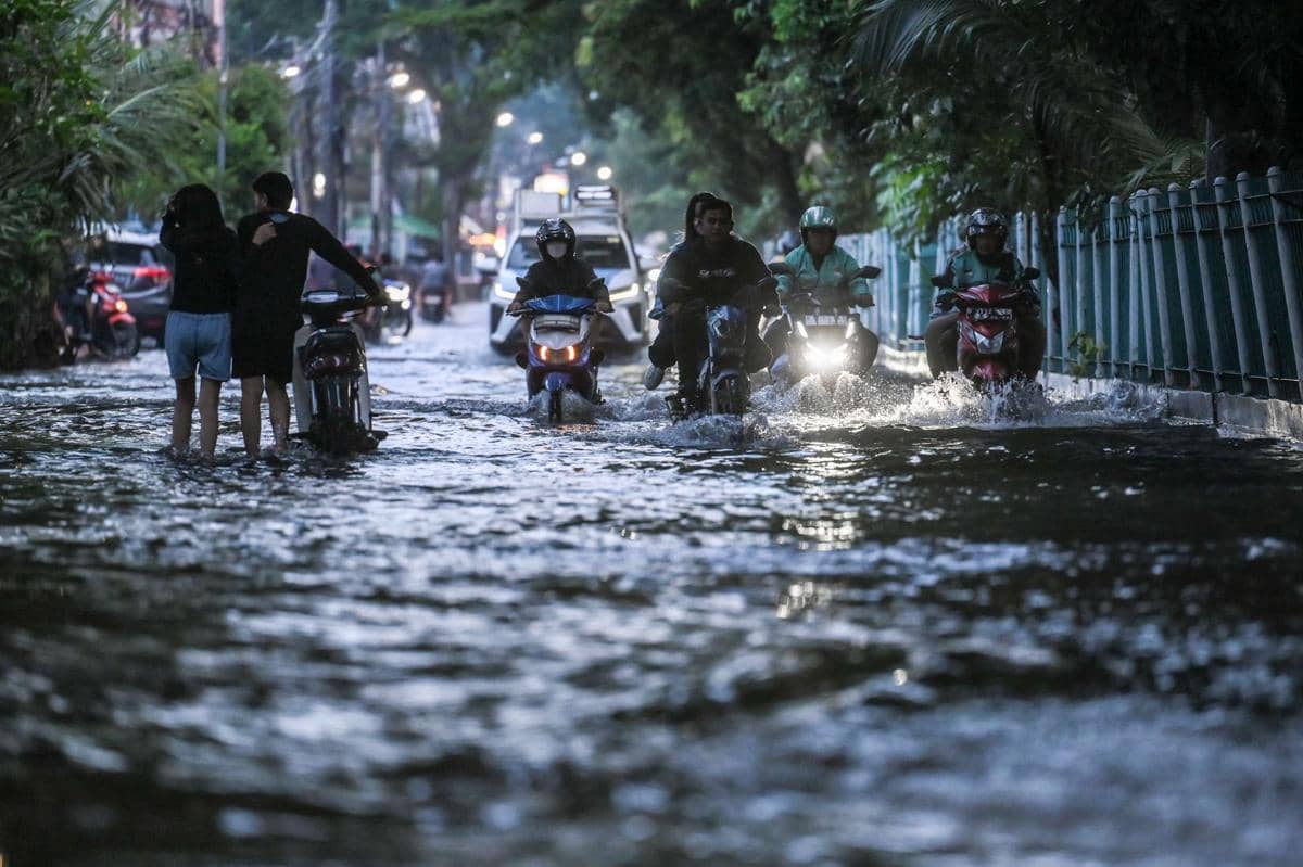 Pengendara melintasi genangan air di kawasan Gunung Sahari, Jakarta, Minggu (18/1/2026).
