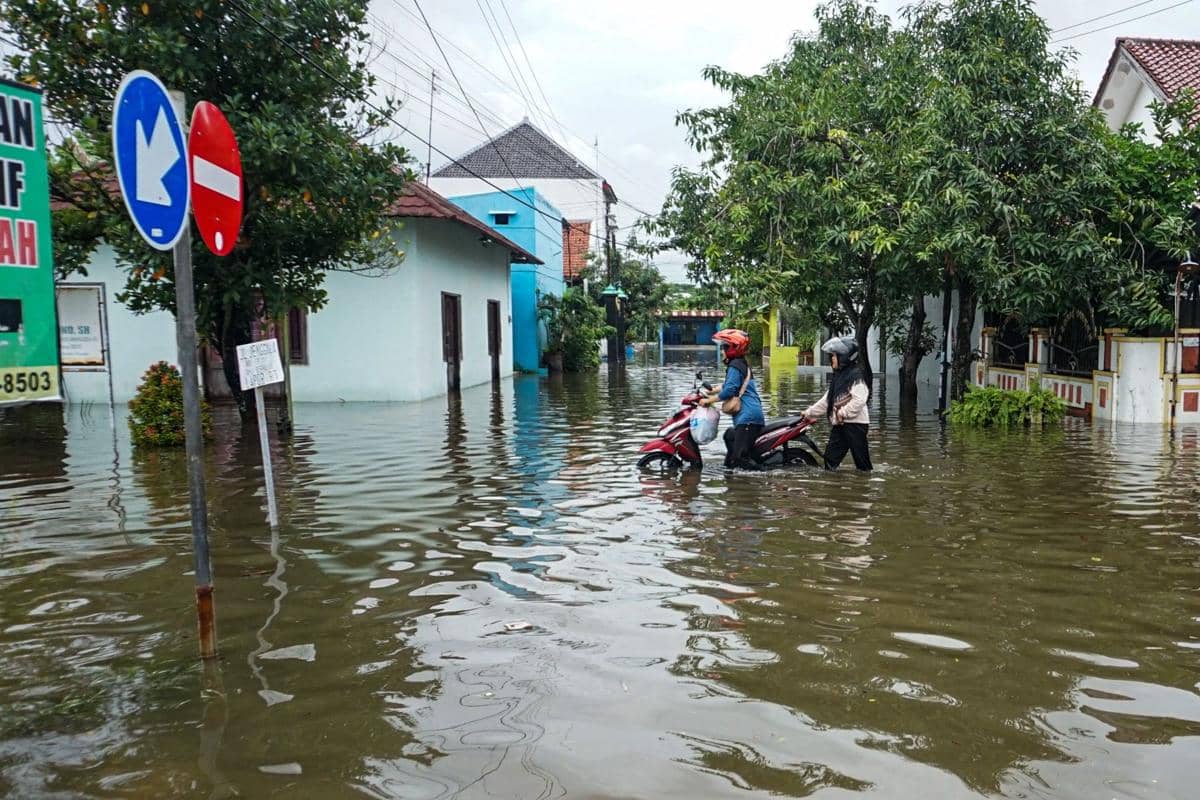 Warga mendorong motornya melintasi banjir di Kampung Baru, Kota Pekalongan, Jawa Tengah, Sabtu (17/1/2026).