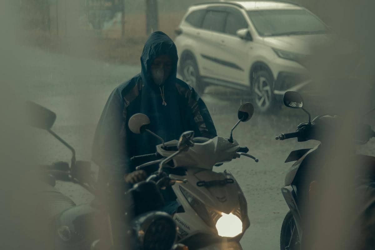 Ilustrasi mengendarai motor saat hujan.