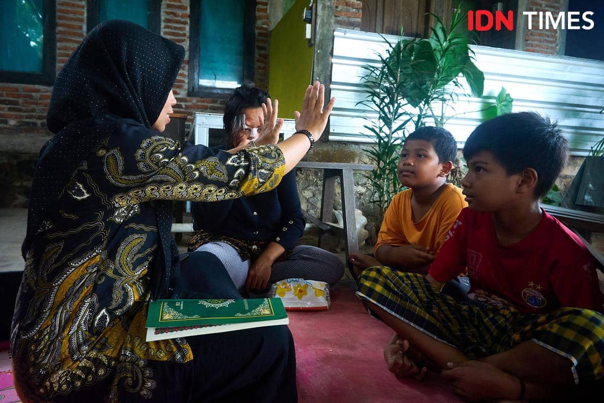 Penyuluh Agama Islam KUA Mijen, Zahrotun Nisa (kiri) mengajarkan tata cara Tayamum kepada Ernawati (kedua kiri), dan kedua anaknya, Arthur (tengah) dan Marco (kanan), yang difabel di Semarang, Kamis (15/1/2026). (IDN Times/Dhana Kencana)