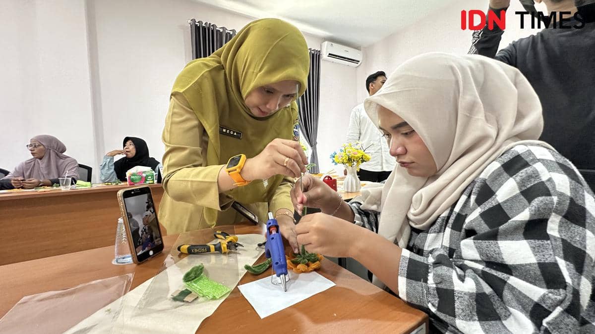 Staf Dinas Perpustakaan Kota Pontianak mengajarkan peserta membuat bouqet bunga mercy.