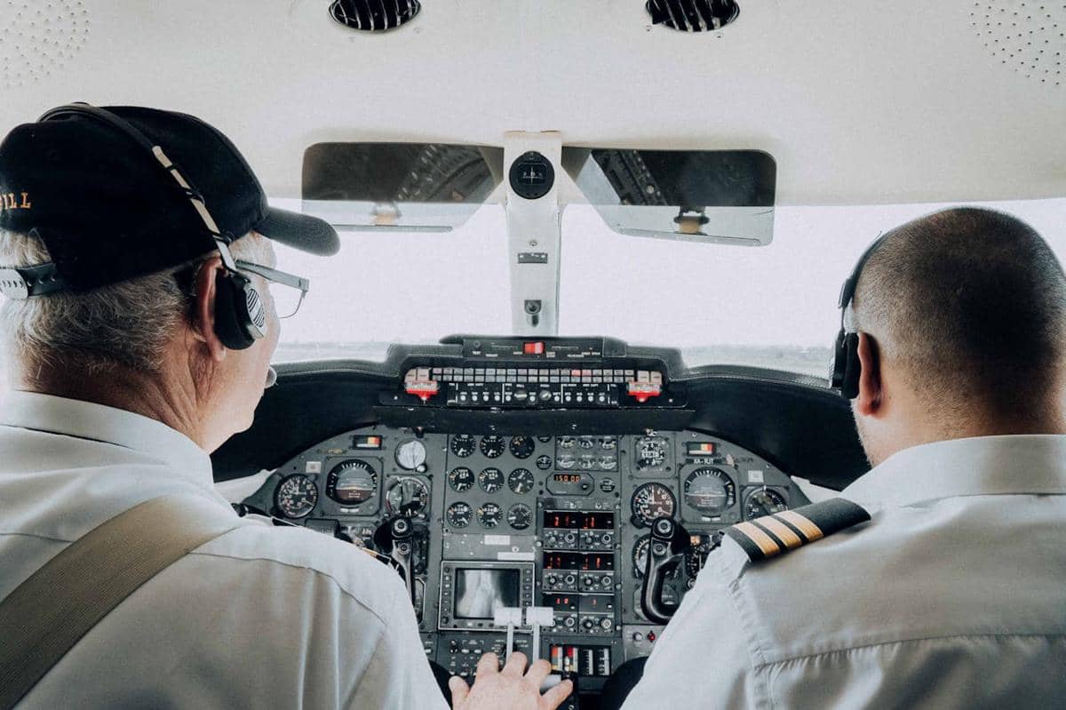 Pilot sedang mengemudikan pesawat terbang.
