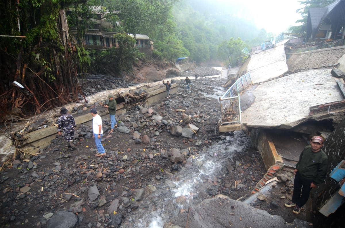 Warga berada di dekat bangunan yang rusak diterjang banjir bandang di Obyek Wisata Guci, Kabupaten Tegal, Jawa Tengah, Minggu (25/1/2026). (ANTARA FOTO/Oky Lukmansyah)