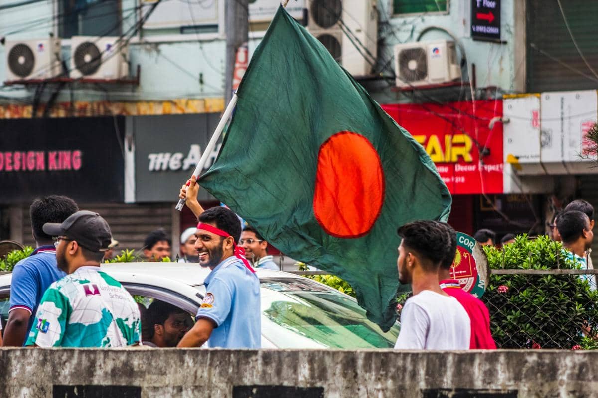 Warga Bangladesh sedang mengibarkan bendera.