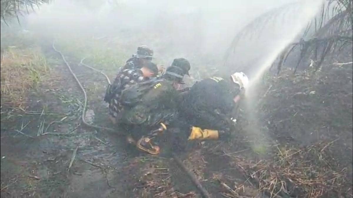 Petugas pemadam karhutla berlindung dari kepulan asap tebal.