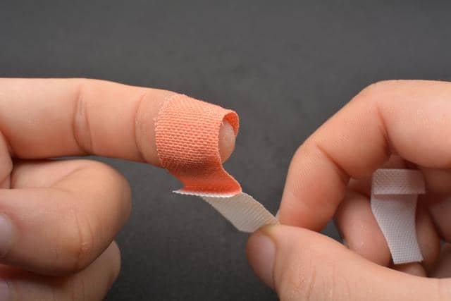 Membalut luka di jari dengan plester.