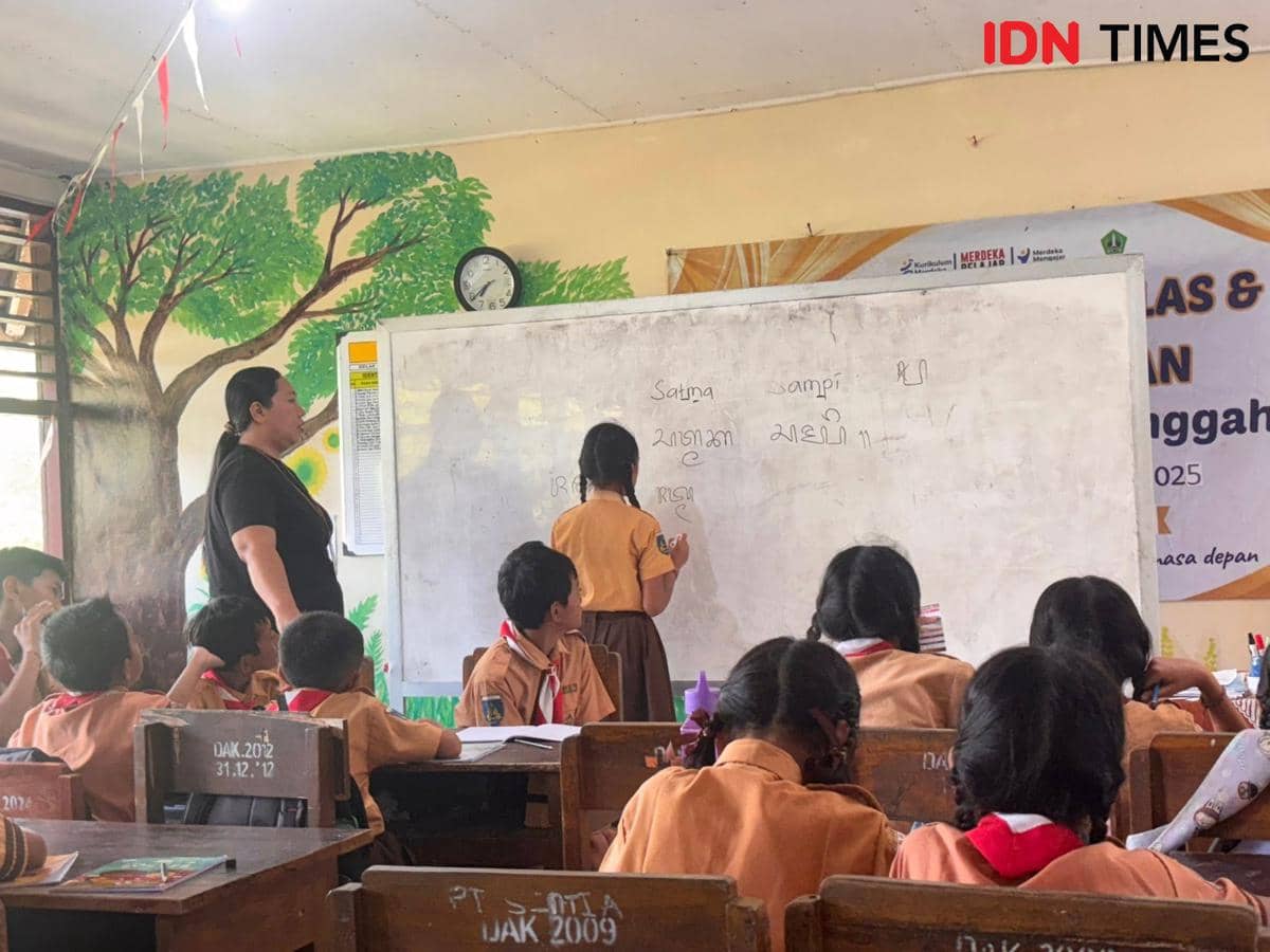Ilustrasi seorang guru berdiri di depan kelas dengan papan tulis sambil mengajar murid-murid di Tabanan, Bali.