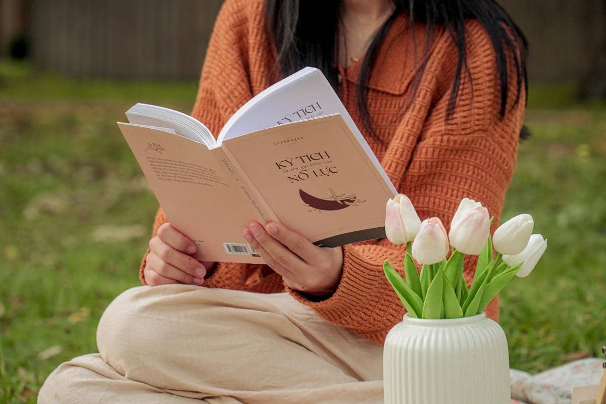 seorang wanita membaca buku di taman 