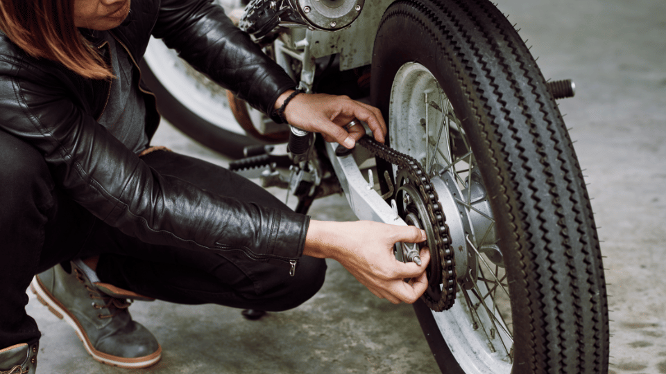seseorang memeriksa gir dan rantai motornya
