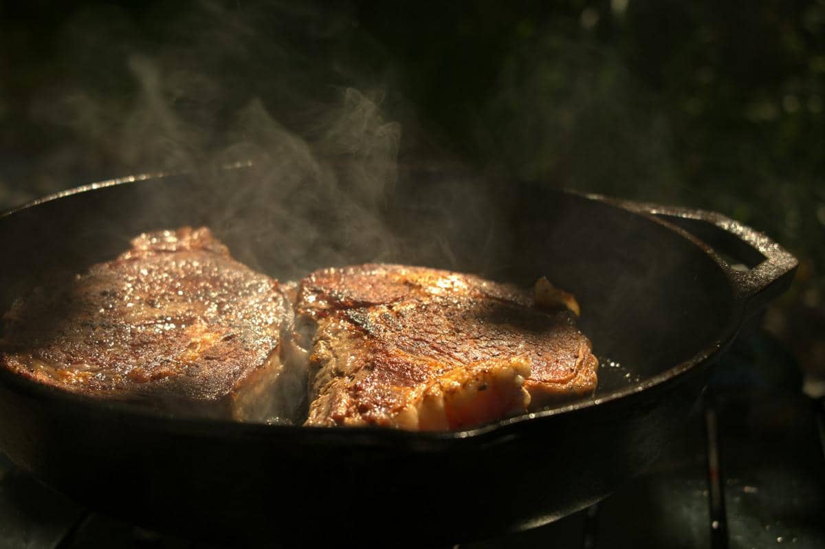 Ilustrasi proses memasak steak di dapur sebagai gambaran pengolahan daging sapi untuk disajikan sebagai hidangan.