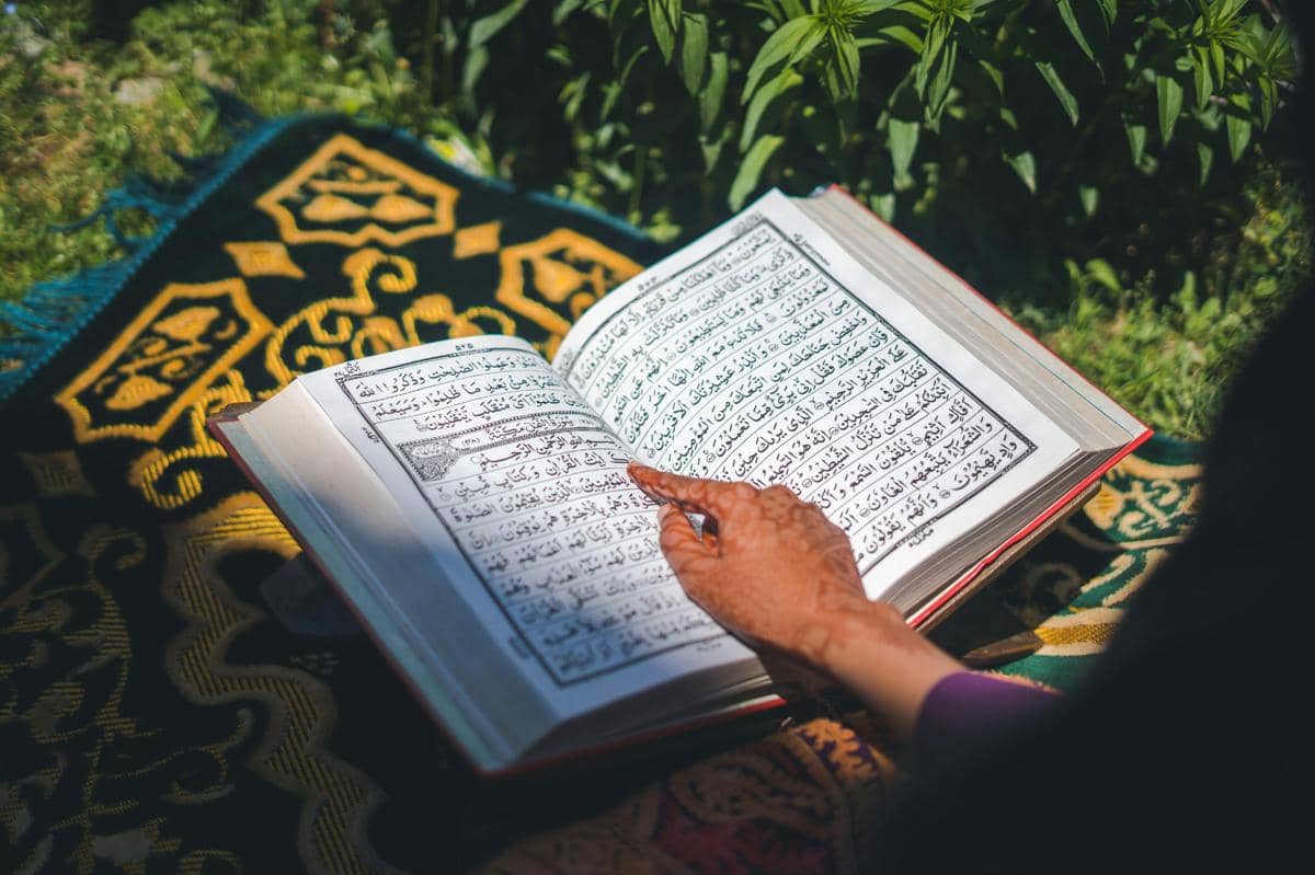 Ilustrasi seseorang membaca Al-Qur’an di atas sajadah