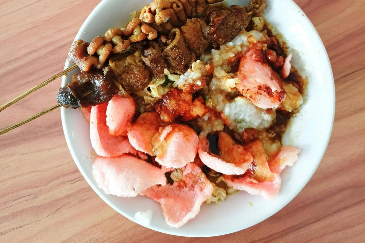 Ilustrasi bubur ayam dengan topping sate-satean.