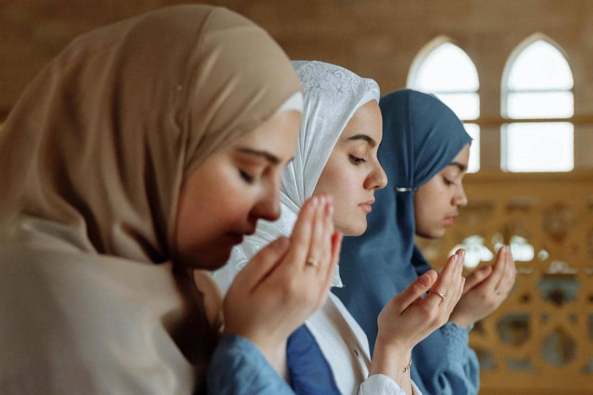Tiga orang perempuan sedang berdoa.