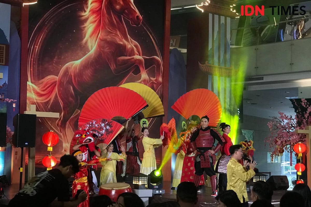Pemain musikal Mulan menampilkan adegan teatrikal dengan kostum prajurit dan properti kipas besar di panggung Ciputra World Surabaya saat perayaan Imlek 2026