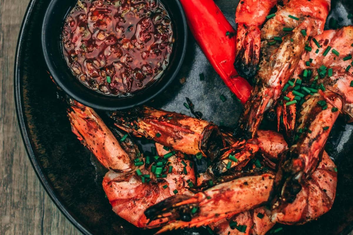 Ilustrasi hidangan seafood saus merah di meja makan bersama.