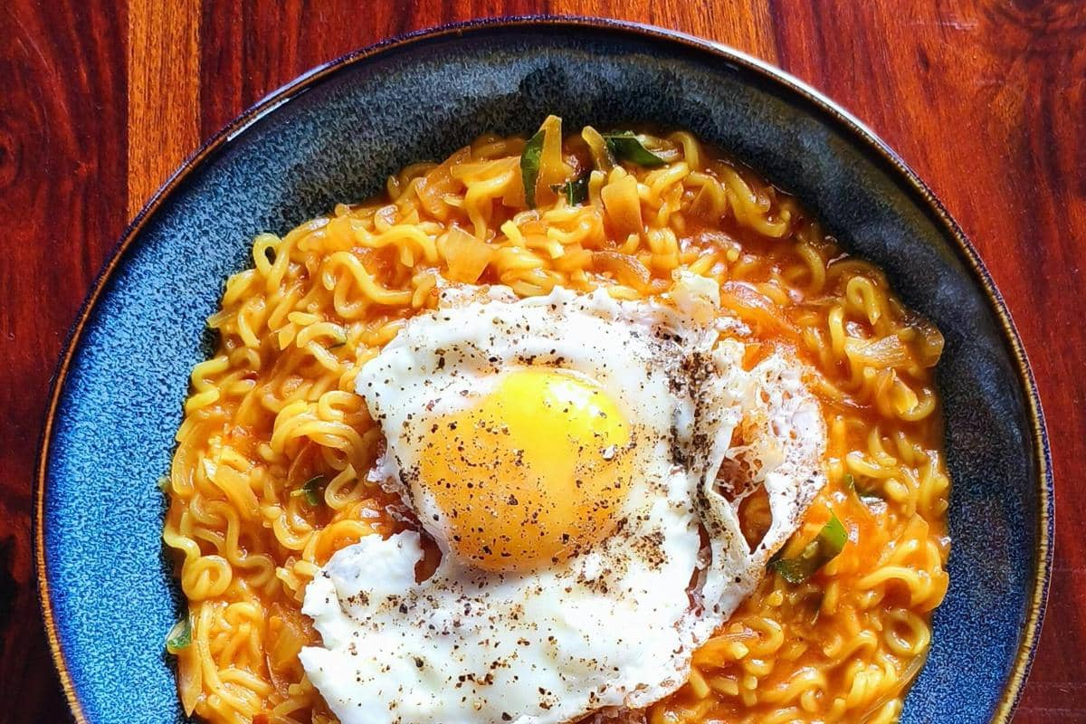 Ilustrasi mie pedas dengan topping telur.