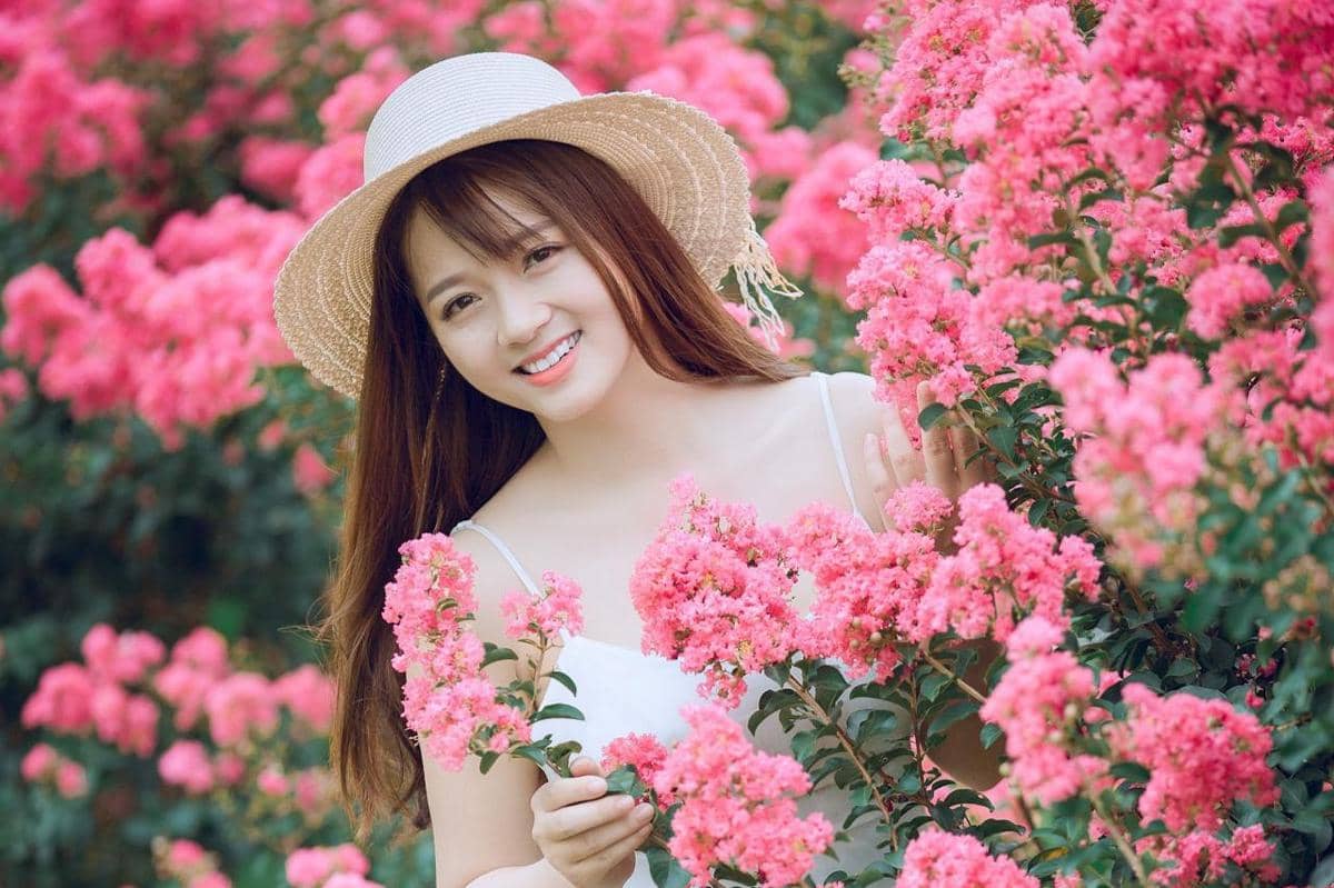 Seorang wanita sedang berada di antara bunga-bunga.