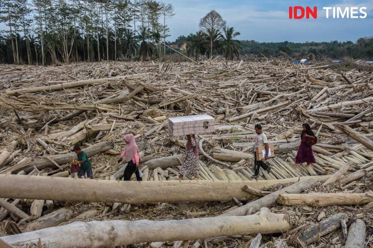 Warga membawa logistik donasi dari para relawan di Kampung Sekumur, Kecamatan Sekerak, Kabupaten Aceh Tamiang, Rabu (21/1/2026). (IDN Times/Prayugo Utomo)