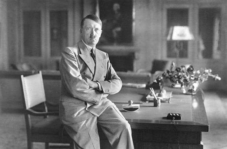 Adolf Hitler sedang duduk di kursi.