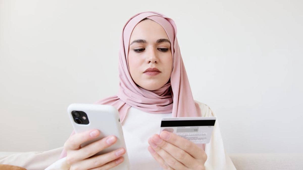 ilustrasi wanita berhijab memegang ponsel dan kartu