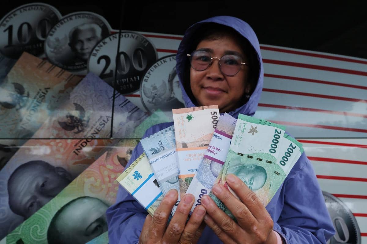 Ilustrasi warga memperlihatkan uang rupiah hasil penukaran di mobil kas keliling Bank Indonesia. (ANTARA FOTO/Jessica Wuysang)